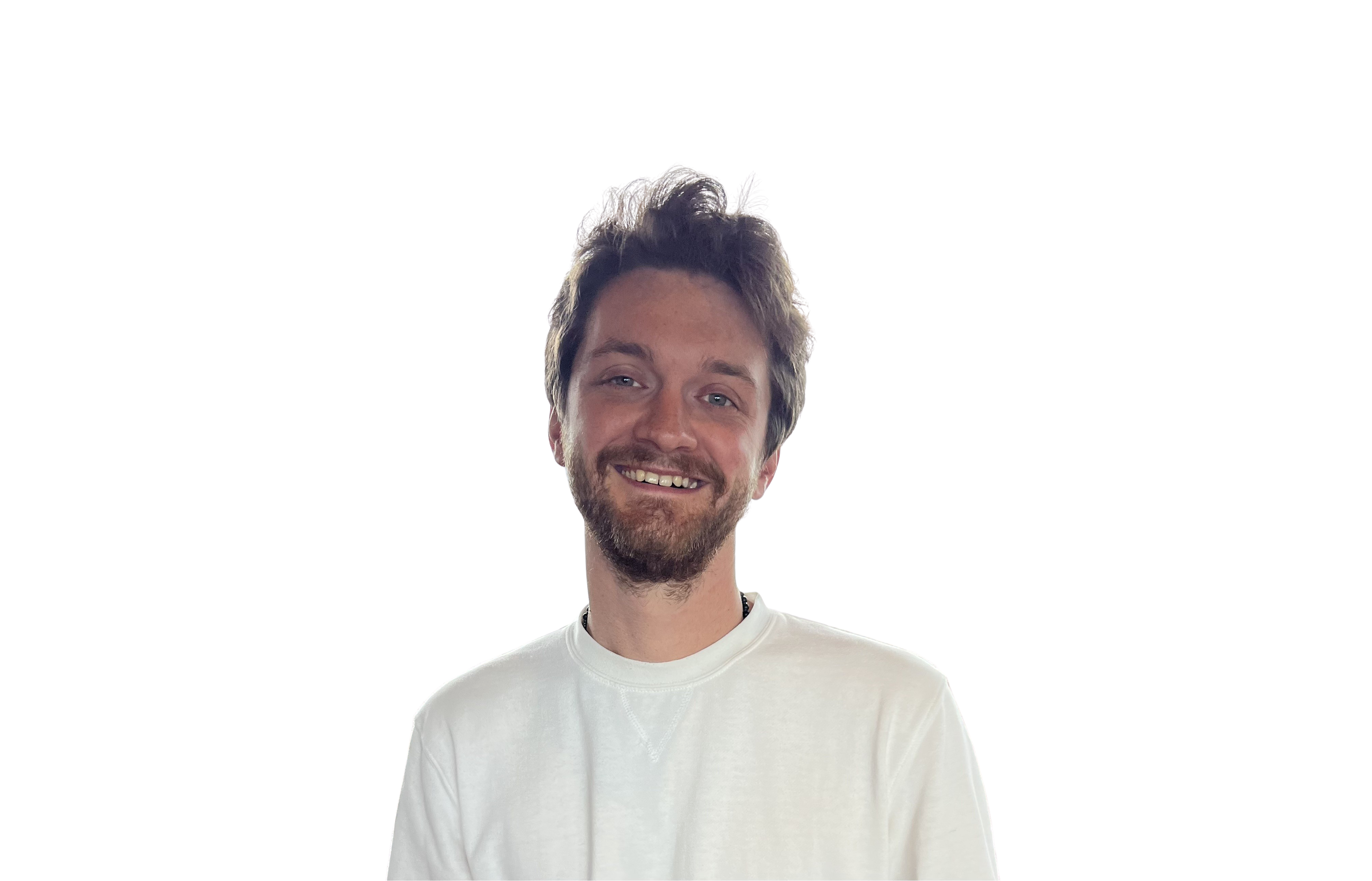 A grinning, bearded man with green eyes and short brown hair